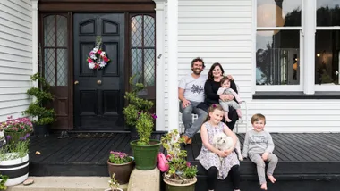 Oamaru villa homeowners sitting in front of their front door with their kids