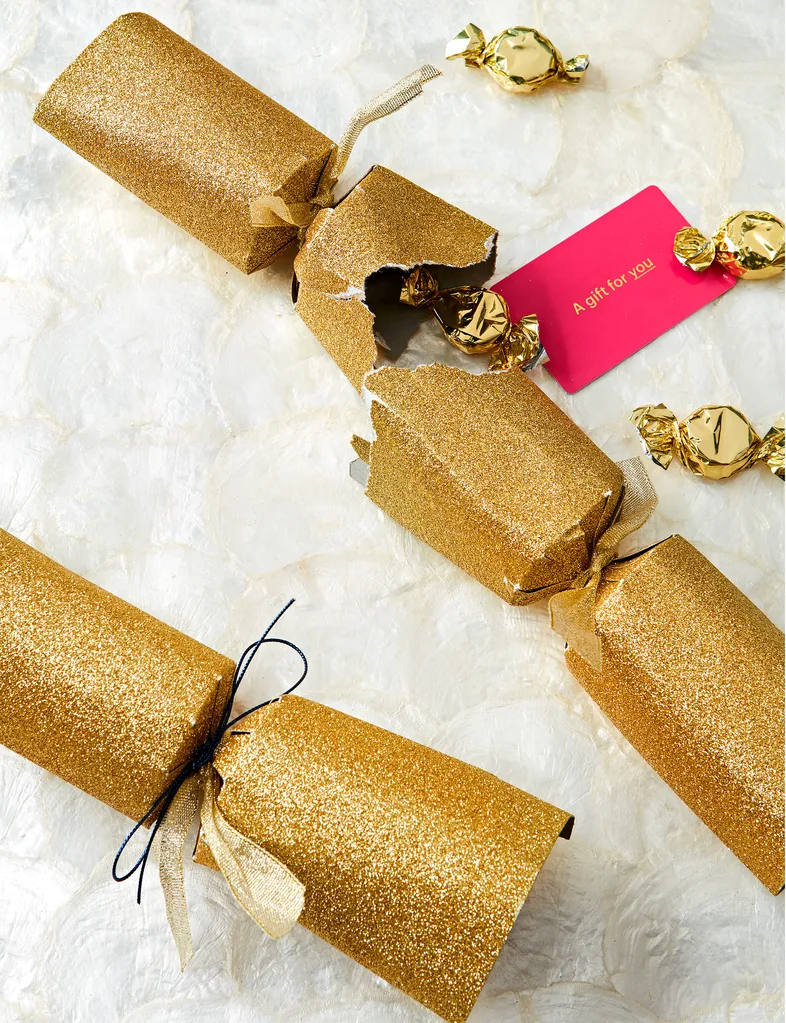 Two golden Christmas crackers with vouchers inside.