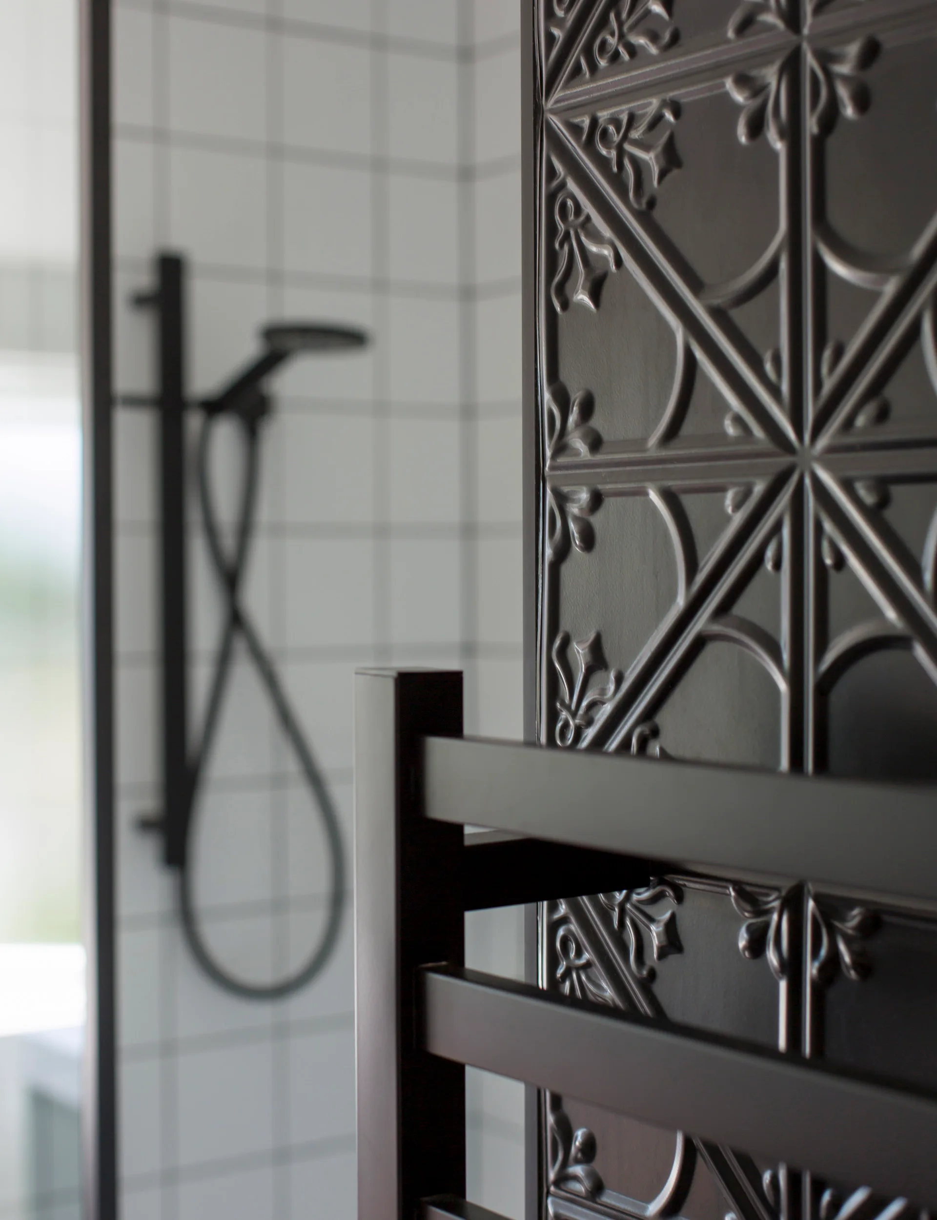 The black wall beside the black shower head in the black white and pink bathroom