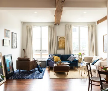 Cozy living room with sofas, guitar, framed art, and large windows.
