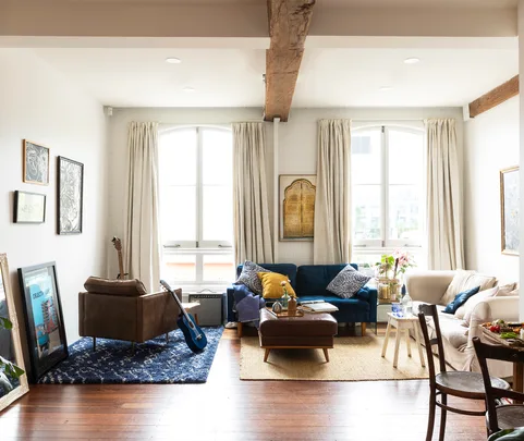 Cozy living room with sofas, guitar, framed art, and large windows.