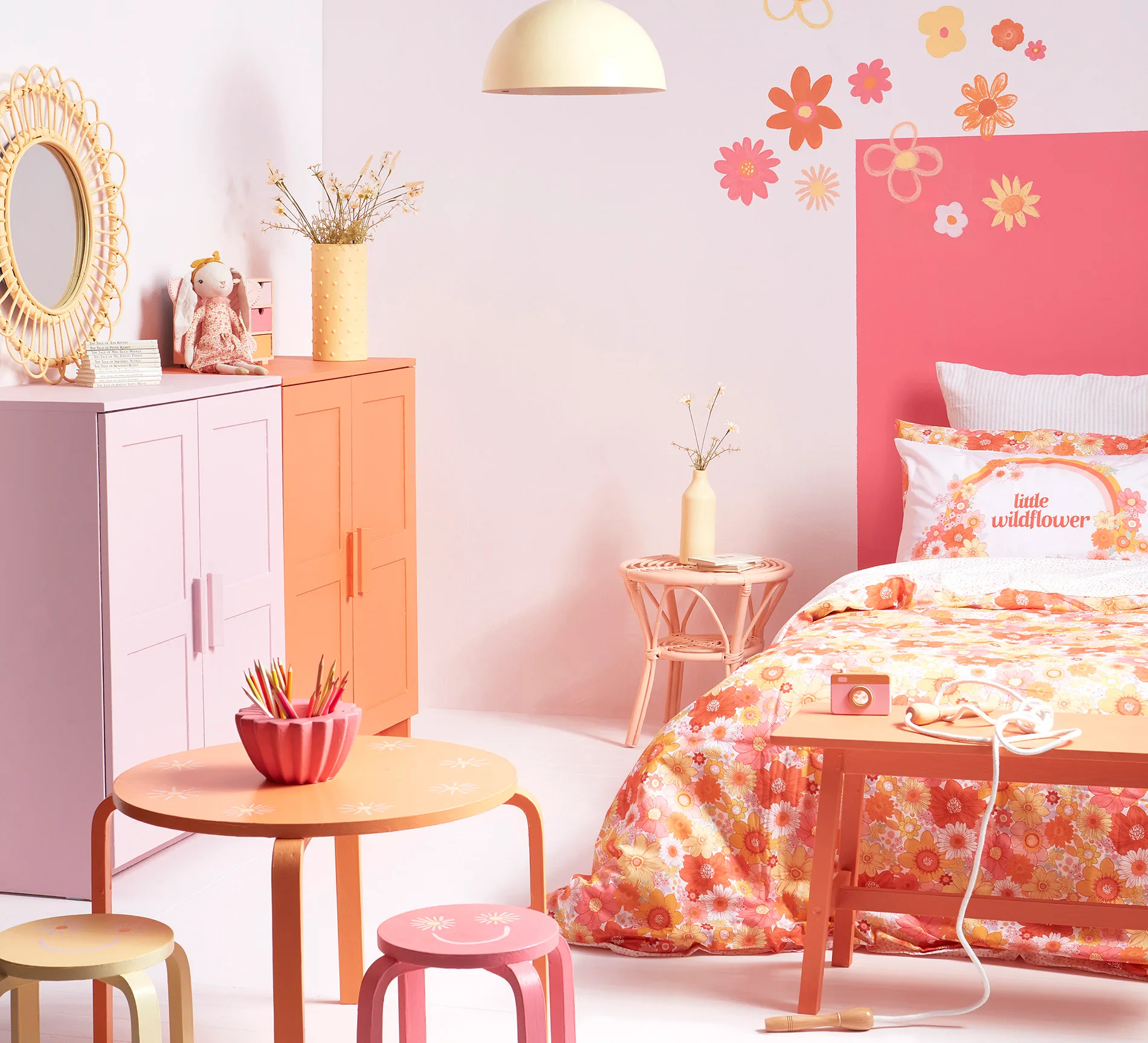 Colorful children's room with floral patterns, pink and orange accents, round table, and decorative pillows.