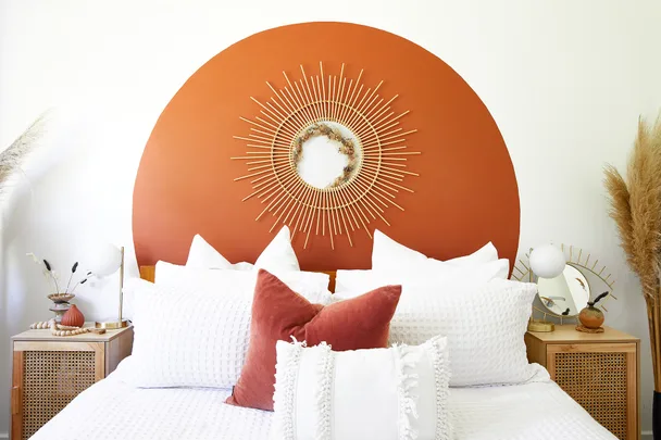 Stylish bedroom with a rust-colored circular headboard, white pillows, and decorative wall art above the bed.