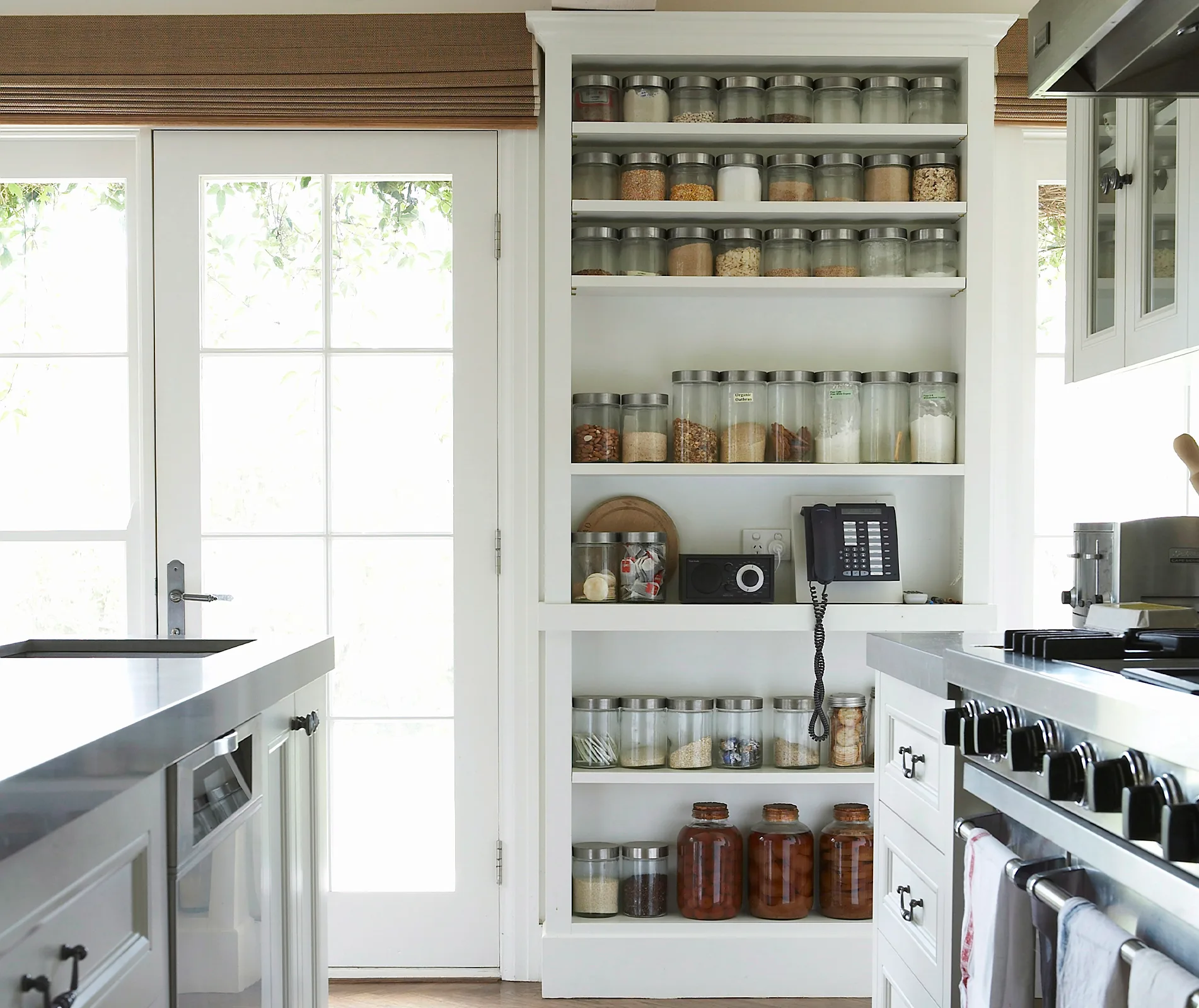Spacious kitchen with wall jars, modern appliances, and natural light from French doors.