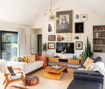 Living room with a gallery wall, modern furniture, plants, and a wooden coffee table, featuring framed pictures.