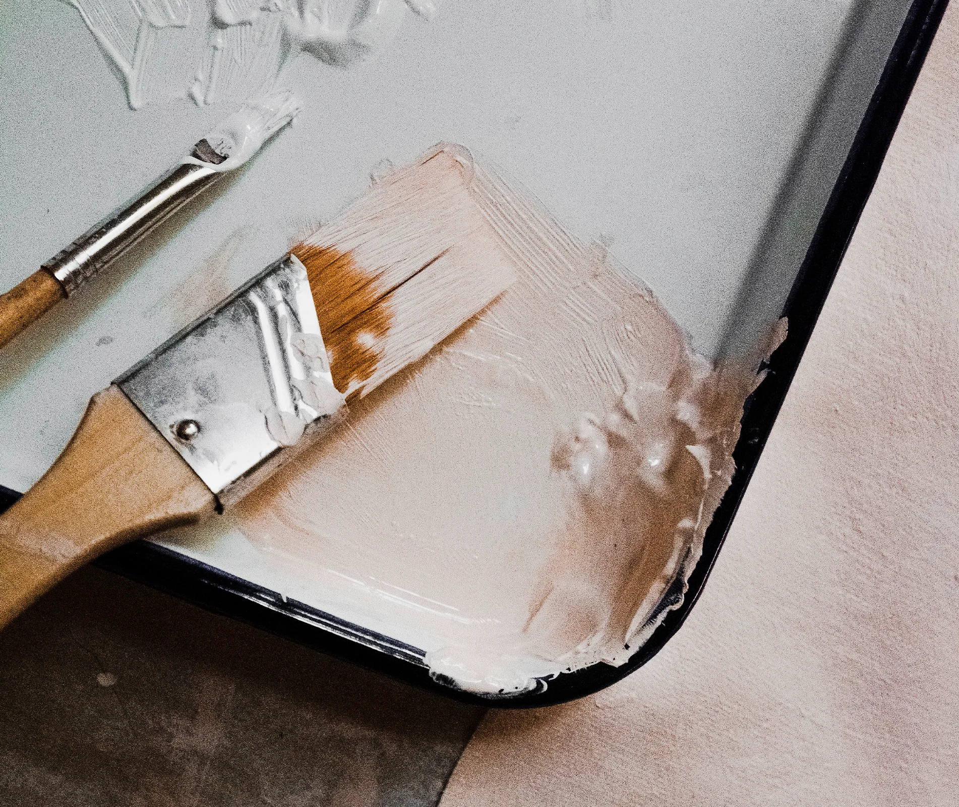 Paintbrush resting on a tray with white paint, suggesting a painting or DIY project in progress.