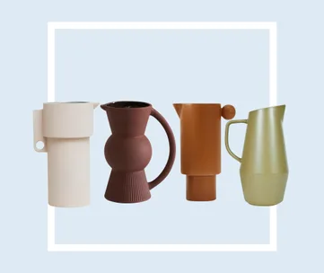 Four modern, minimalist pitchers in varying shapes and earth tones against a light blue background.