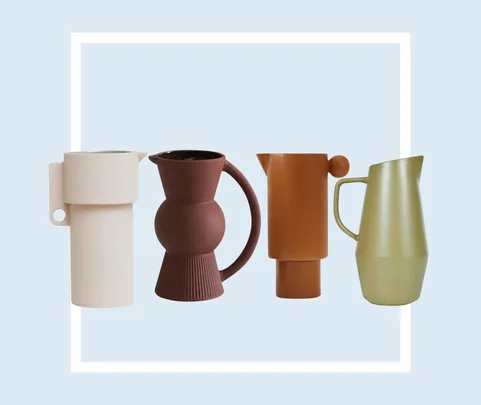Four modern, minimalist pitchers in varying shapes and earth tones against a light blue background.
