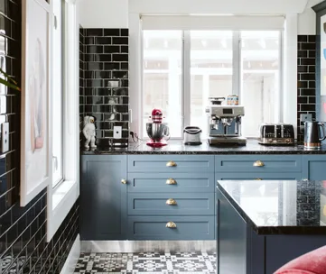 Modern kitchen with black tiles, gray cabinets, coffee machine, red mixer, and patterned floor.