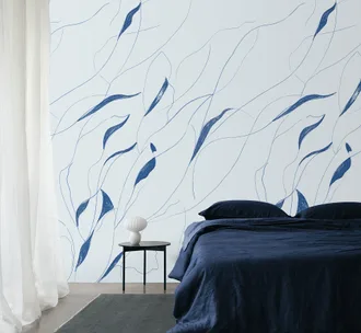 Bedroom with a navy blue bed, abstract blue leaf-patterned wall, sheer curtains, and a small side table with a white vase.