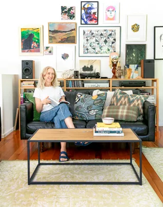 A person sitting on a couch reading a book in a living room with colorful artwork on the wall.