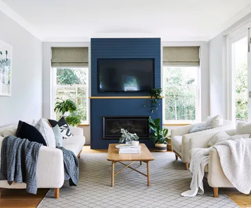 Stylish living room with navy accent wall, modern fireplace, and beige sofas arranged around a wooden coffee table.
