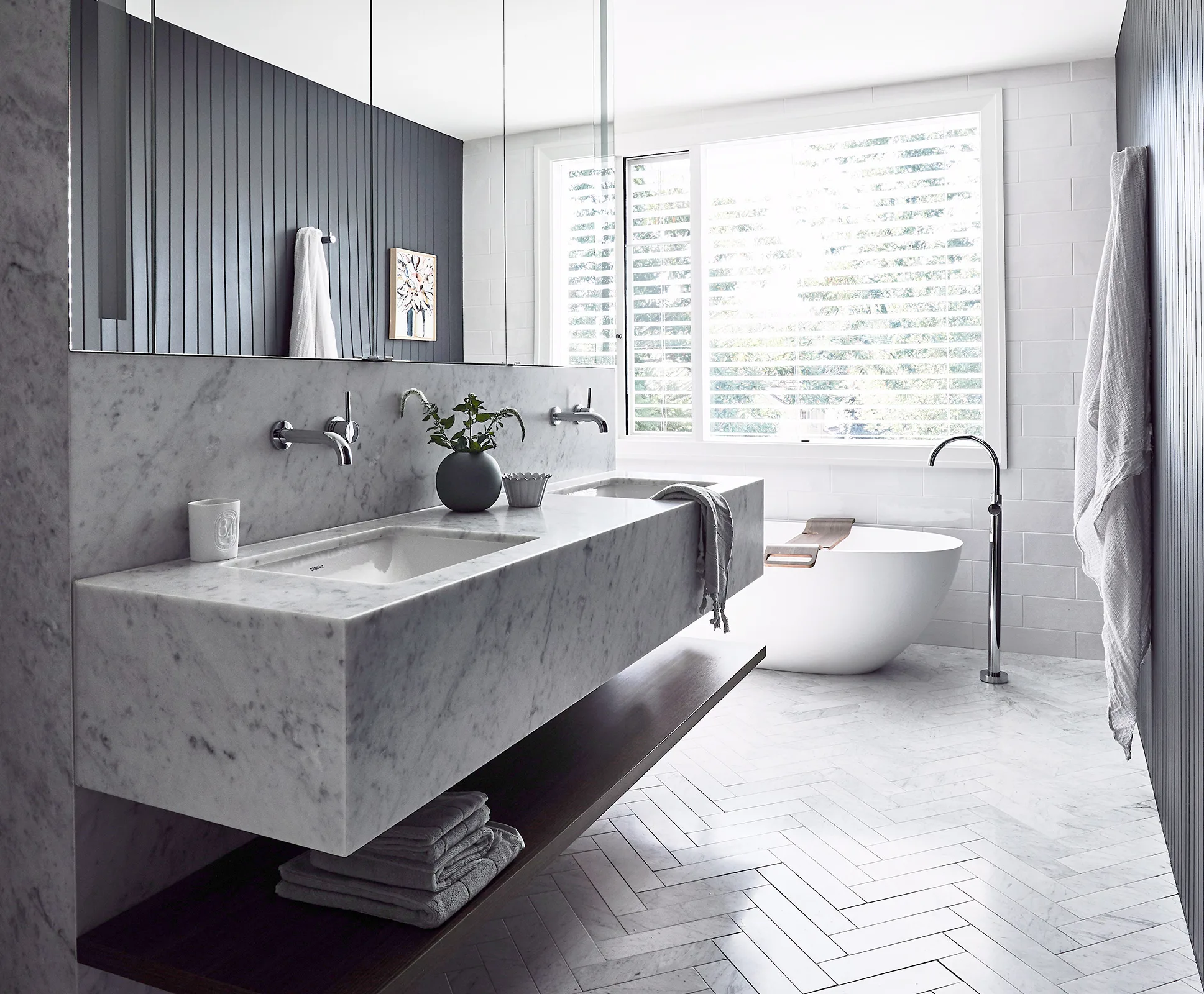 Luxurious bathroom with marble sink, freestanding tub, and large window with blinds.