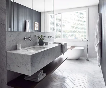 Luxurious bathroom with marble sink, freestanding tub, and large window with blinds.
