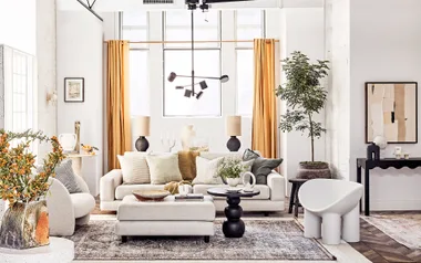 Modern living room with neutral sofas, mustard curtains, abstract art, and potted plant.