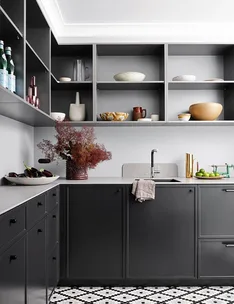 Modern kitchen with dark cabinets, open shelves displaying ceramics, and a patterned black-and-white tile floor.