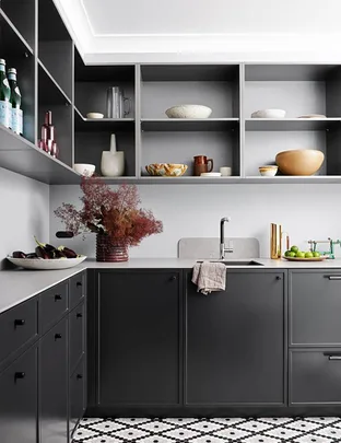 Modern kitchen with dark cabinets, open shelves displaying ceramics, and a patterned black-and-white tile floor.