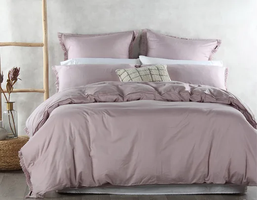 Lavender bedding set on a neatly made bed with decorative pillows and a rustic ladder beside.