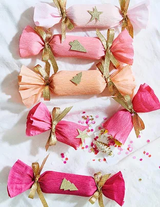 Colorful Christmas crackers with gold ribbons and decorations on a white background.