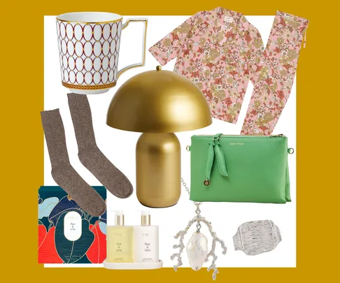 A collection of gift items including a mug, floral pajamas, green clutch, gold lamp, socks, skincare products, and jewelry.