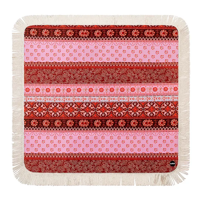 A patterned pink and red beach towel with fringe edges, featuring intricate floral and geometric designs.