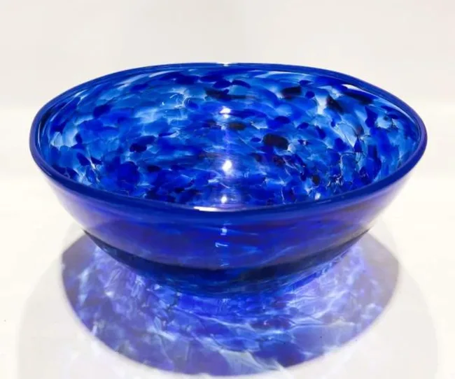 Blue glass bowl with a marbled pattern on a white background.