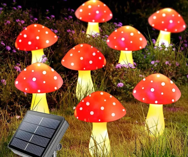 Solar-powered mushroom-shaped garden lights with red caps and white spots illuminating a dark garden.