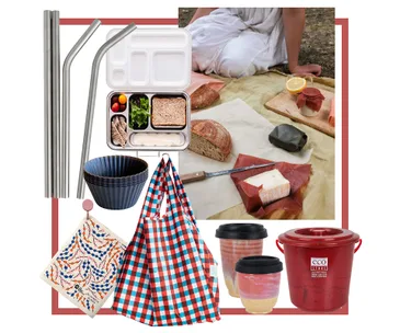 Eco-friendly picnic set with reusable containers, metal straws, checkered bag, utensils, and bread on a picnic blanket.