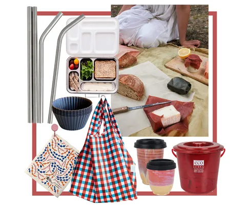 Eco-friendly picnic set with reusable containers, metal straws, checkered bag, utensils, and bread on a picnic blanket.