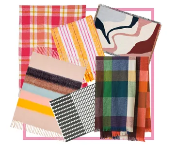 Various colorful patterned throws and blankets are displayed, including plaid, striped, and abstract designs.