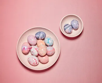 Marbled Easter eggs in pastel colors on pink plates and background.