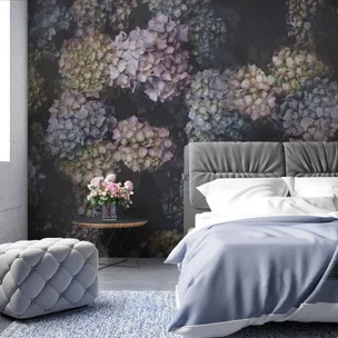 Bedroom with floral wallpaper, gray bed, blue bedding, gray ottoman, and table with pink roses in a vase.