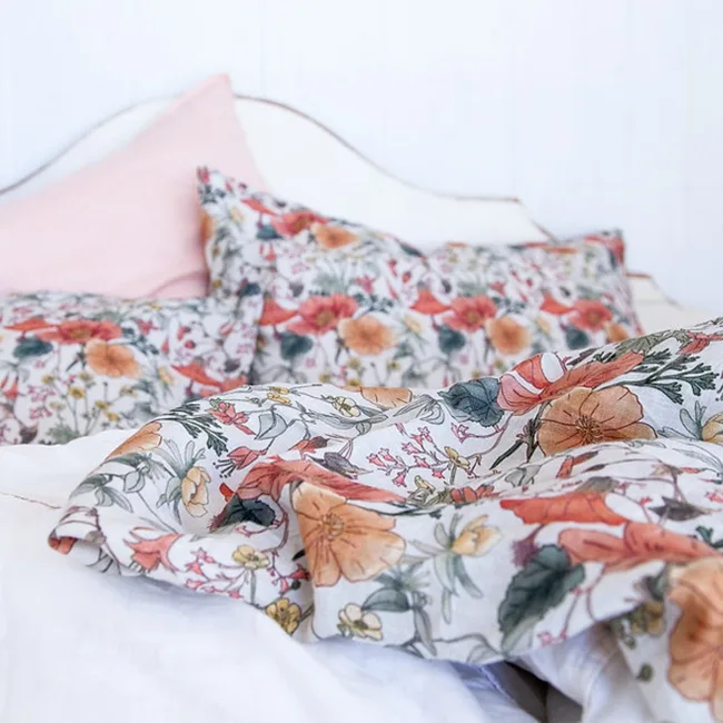 Floral-patterned bedding with vibrant orange and yellow flowers on a bed with a white headboard.
