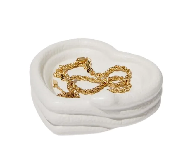 White ceramic heart-shaped dish with a gold chain inside.