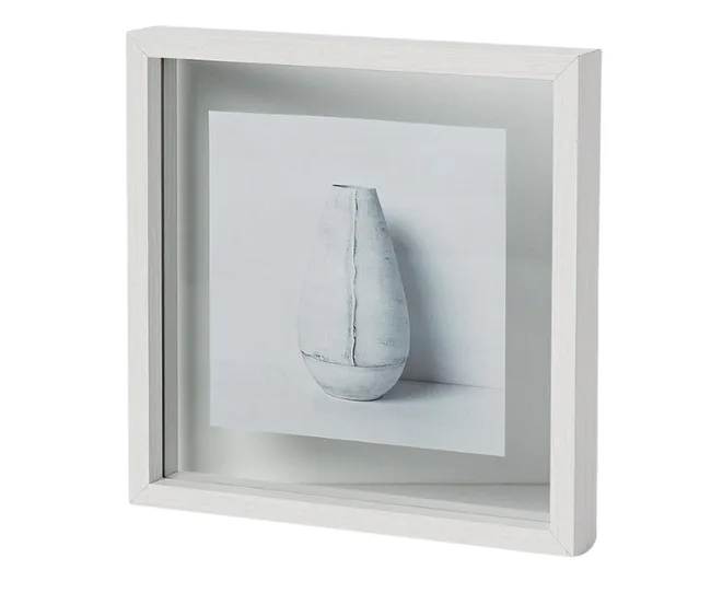 Framed, minimalist black-and-white photo of a ceramic vase, displayed at an angle.
