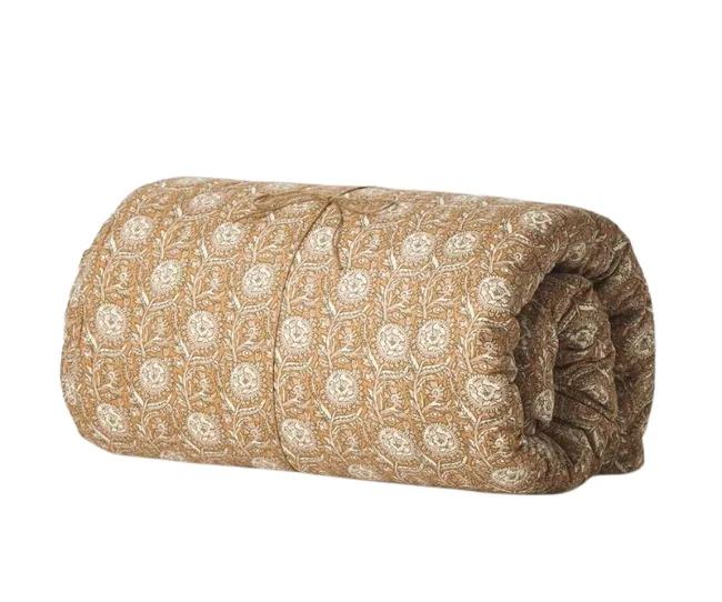 Rolled beige quilt with a floral pattern.