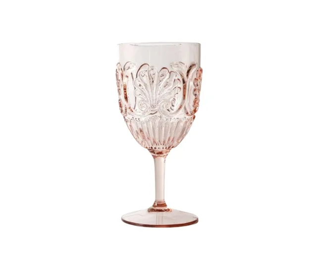 A pink embossed wine glass with ornate patterns on its bowl, standing on a clear stem and base.