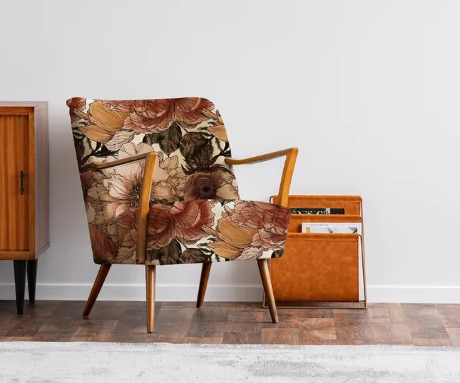 Floral-patterned armchair with wooden frame next to a wooden cabinet and magazine rack in a minimalist room.