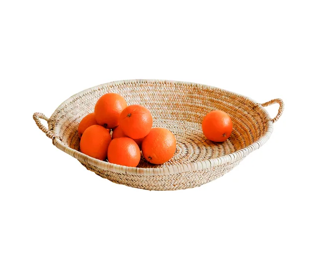 A woven basket holds several bright oranges arranged neatly on a white background.