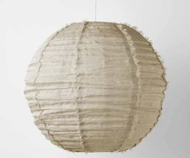Hanging round beige fabric lampshade with a textured, rustic design against a plain background.