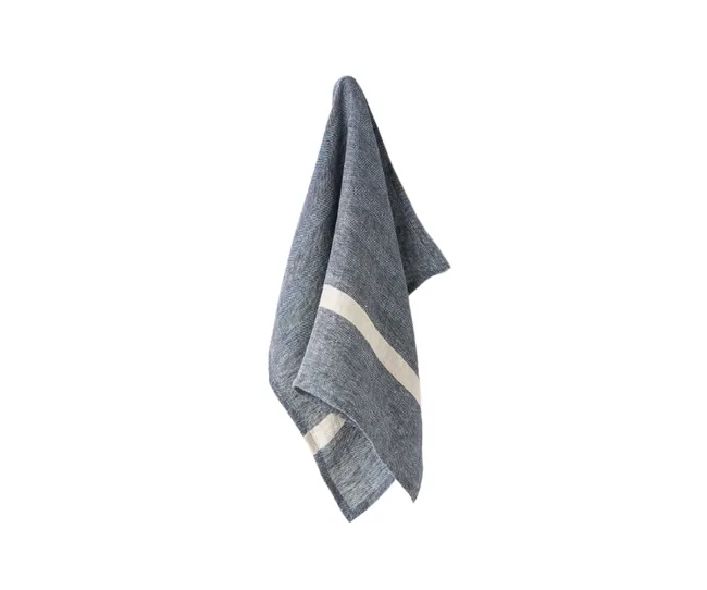 Hanging denim blue linen towel with a white stripe, isolated on a white background.