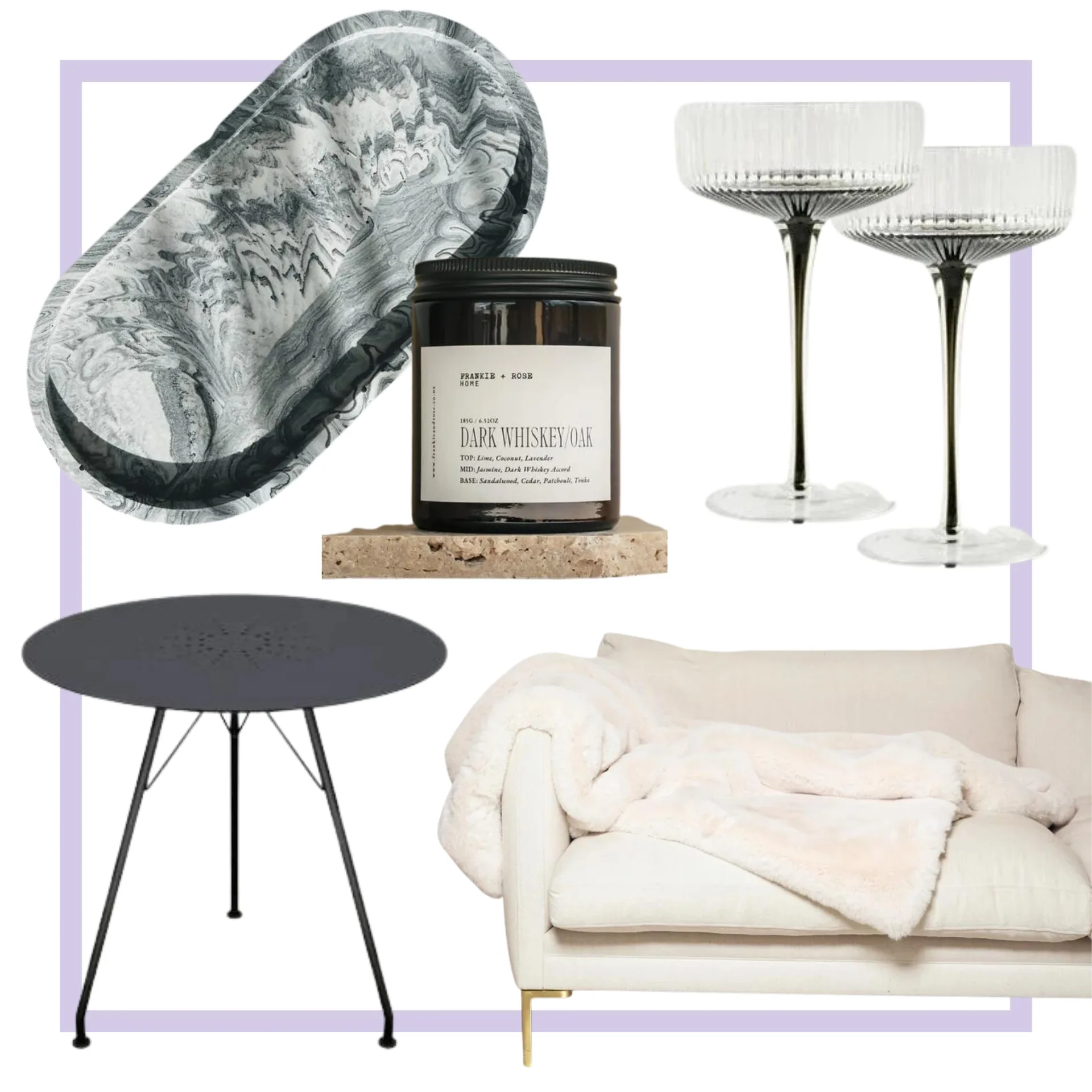 Home decor items: black tray, whiskey oak candle, two glass coupe glasses, black table, white couch with blanket.
