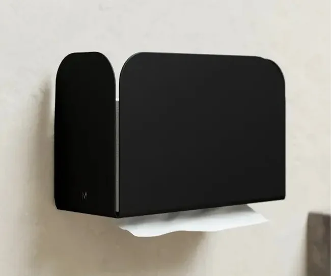Black wall-mounted paper towel dispenser with a white towel protruding.
