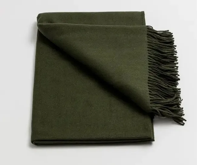 Dark green wool scarf with fringed edges folded neatly over a light background.
