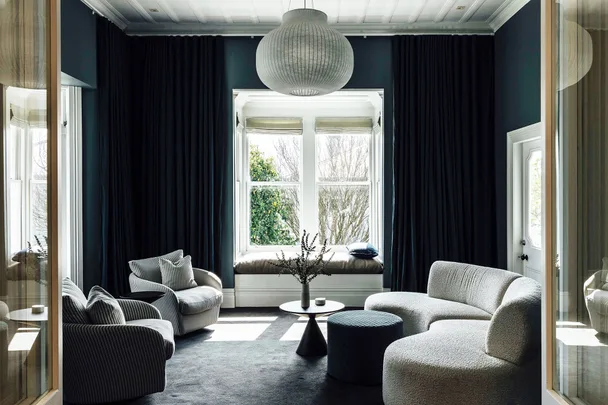 Sophisticated living room with modern furniture, large windows, and a central round light fixture.
