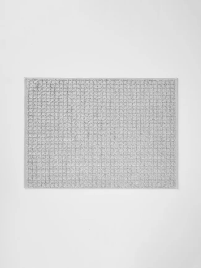 Gray rectangular bath mat with a waffle texture against a white background.