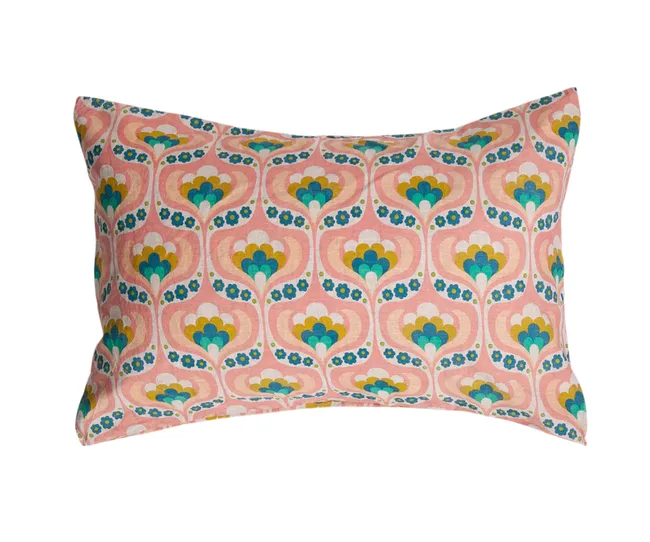 Decorative pillow with a retro floral pattern in pink, blue, yellow, and green on a soft pink background.