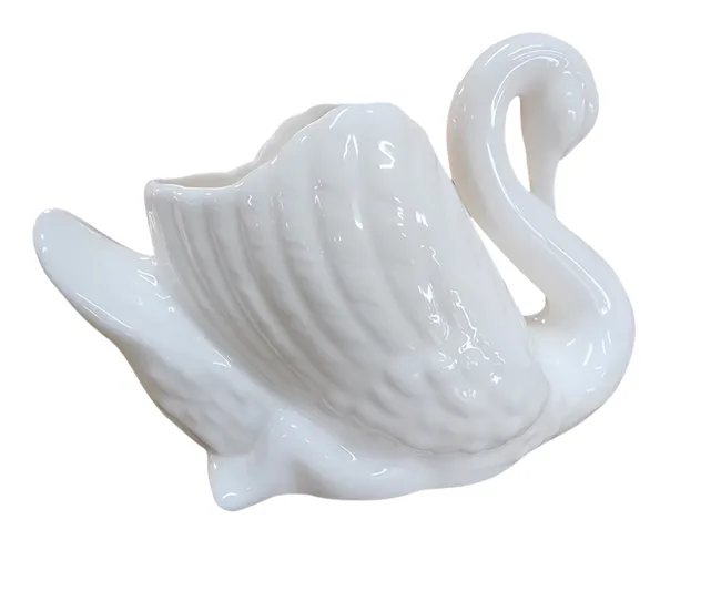 A white ceramic swan with detailed feathers and a curved neck.