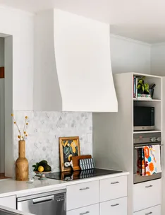 Modern kitchen with white cabinetry, hexagonal tile backsplash, decor items, and stainless steel appliances.