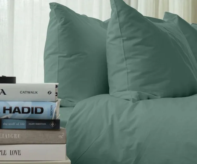 Teal bedding with stacked books beside it, including titles "Catwalk" and "Simple Love."